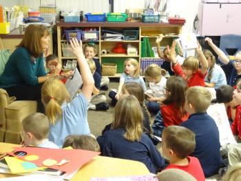 students in classroom raising hands 